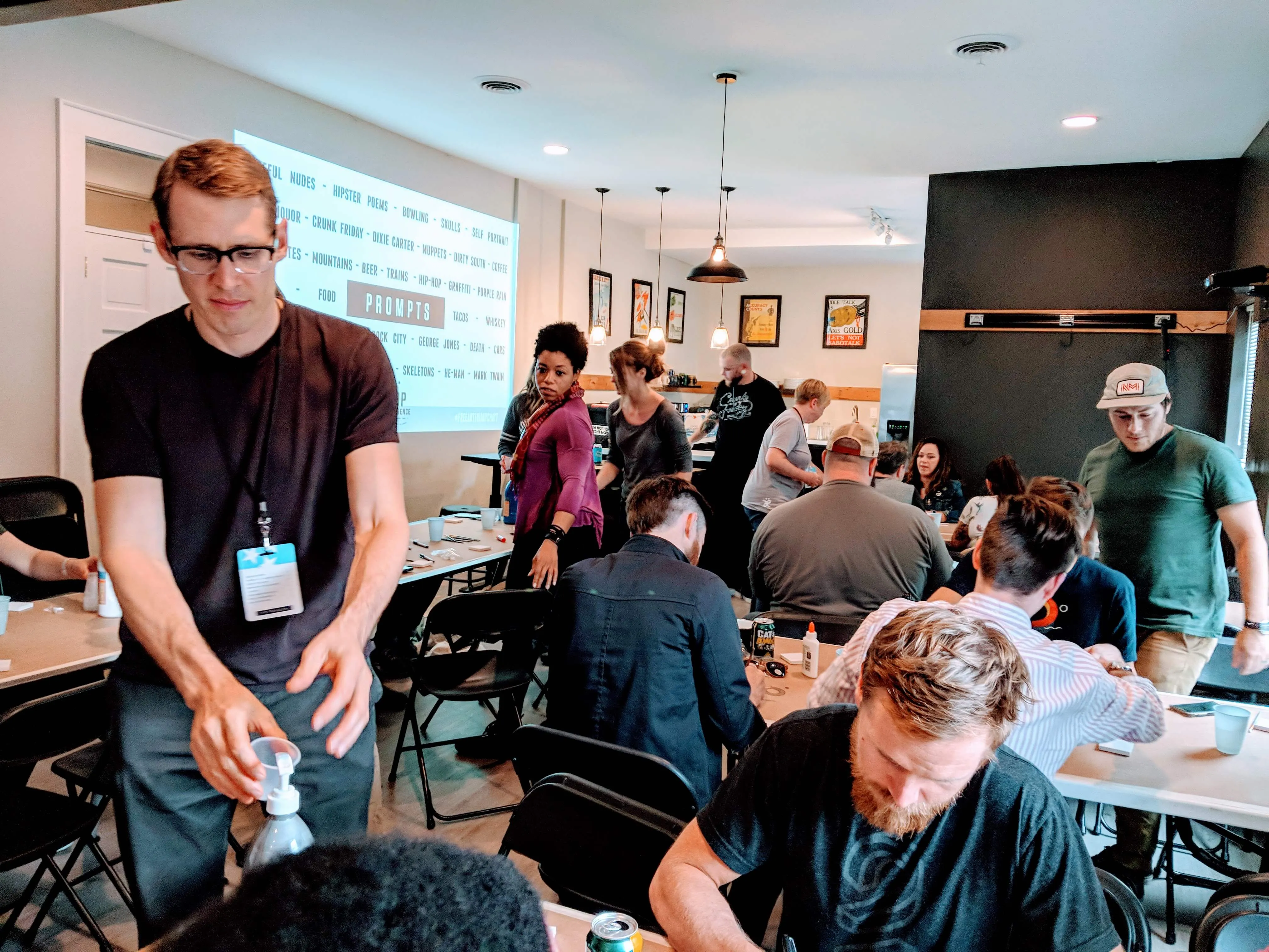 Attendees at the Top Con break out session working at long tables, a screen of drawing prompts projected behind them
